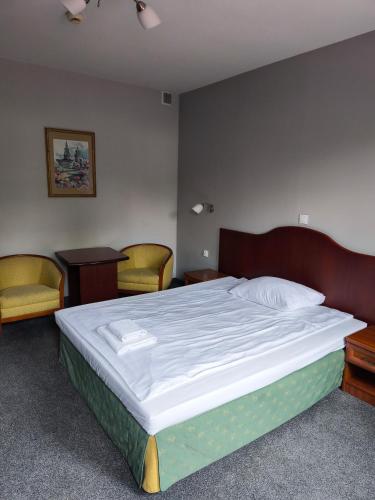 a bedroom with a bed with two chairs and a table at Salis Resort in Wieliczka