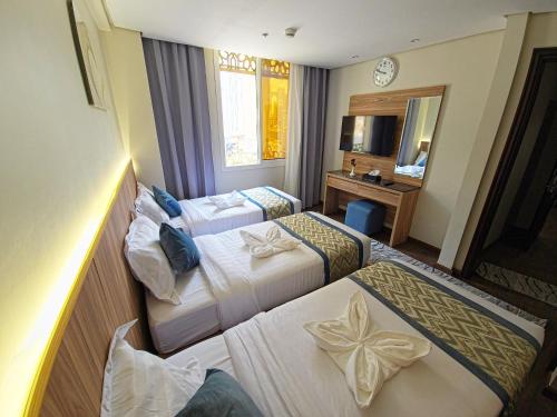 a hotel room with two beds and a mirror at فندق جادة أجياد Jada Ajyad Hotel in Ajyad