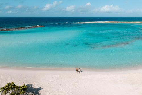 two people walking on a beach near the ocean at Secrets Baby Beach Aruba Adults Only in Ceru Colorado