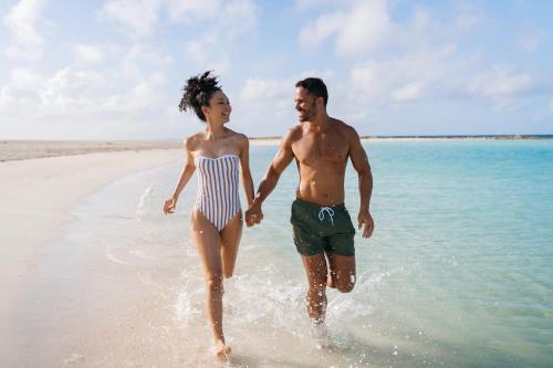 a man and a woman walking on the beach at Secrets Baby Beach Aruba Adults Only in Ceru Colorado