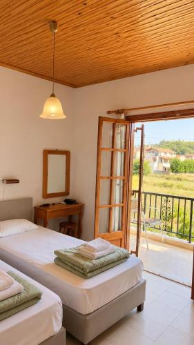 a bedroom with two beds and a mirror and a balcony at Gian Petro Apartments in Sidari