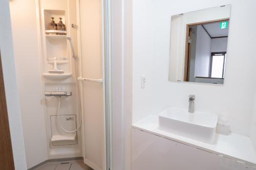 a white bathroom with a sink and a mirror at Kaga Travel - Hakusandai, Whole building for rent in Kaga