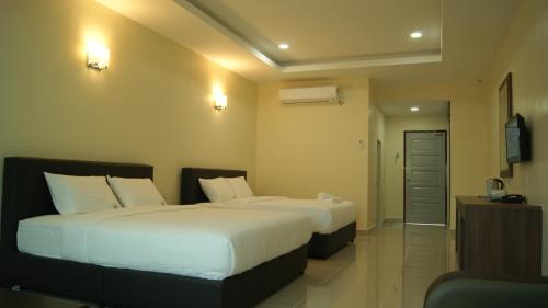 a hotel room with two beds with white sheets at Wang Valley Resort in Pantai Cenang