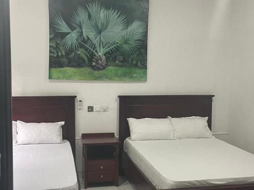 a bedroom with two beds and a painting on the wall at Da Palm boutique resort in Aburi