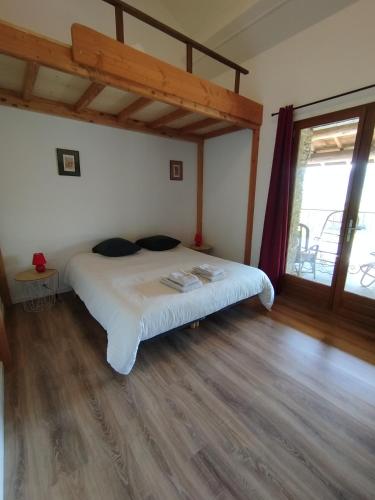 a bedroom with a white bed with a wooden floor at La Bouriotte Gîtes in Labastide-Rouairoux