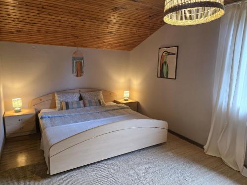 a bedroom with a large white bed and a chandelier at Kopitnik cosy cabin in Dol pri Hrastniku