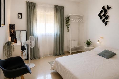 a bedroom with a white bed and a black chair at Kyel location in Ashdod