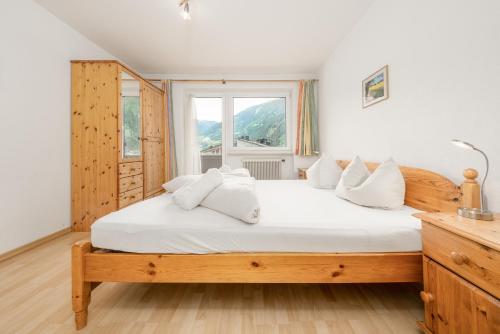 a bedroom with a bed with white sheets and a window at Haus St. Christoph in Mayrhofen