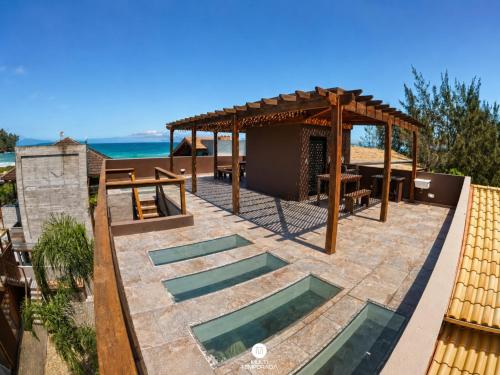a patio with a pergola and a swimming pool at Residencial La Ferrugem - Garopaba/SC in Garopaba