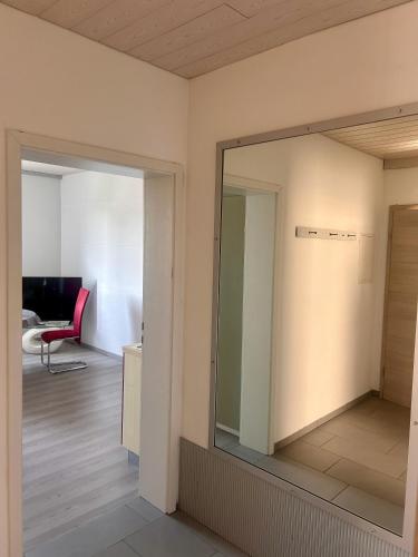 a mirror in a room with a red chair at Ferienwohnung im Herzen Backnangs - 2 Zimmer in Backnang