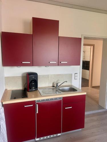 a kitchen with red cabinets and a sink at Ferienwohnung im Herzen Backnangs - 2 Zimmer in Backnang