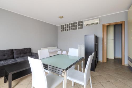 a dining room with a glass table and white chairs at Turin Airport apt G in Leinì