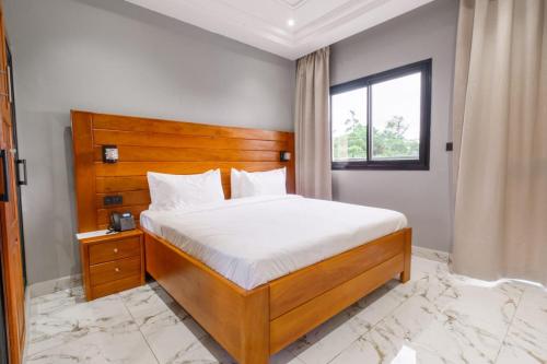 a bedroom with a bed with a wooden headboard and a window at Logements Majeo in Kribi