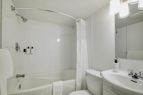 a white bathroom with a toilet and a sink at Hotel Newstar Montréal in Montreal