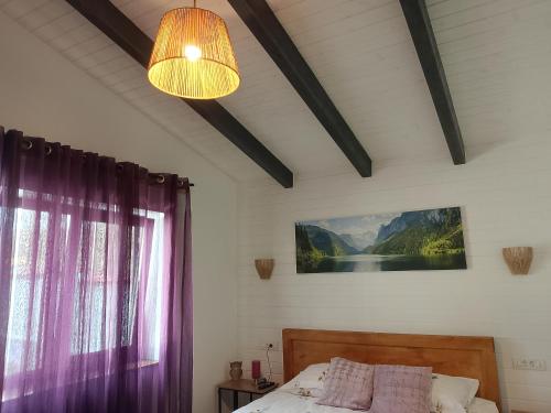 a bedroom with a bed with purple curtains and a chandelier at Luca`s Chalet Ocnele Mari in Ocnele Mari