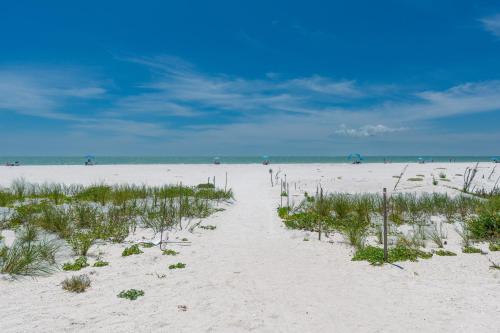 a sandy beach with people in the ocean on a cloudy day at Lovers Key #508 by Sun Palace Vacations in Fort Myers Beach