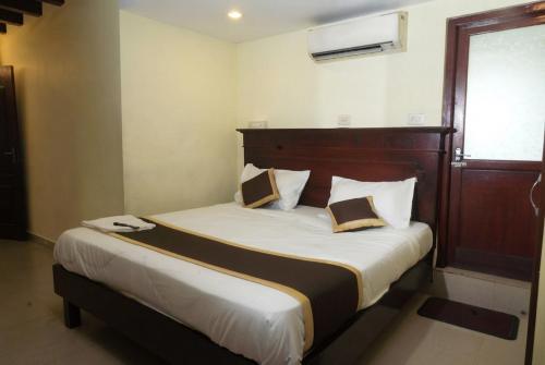 a bedroom with a large bed with a wooden headboard at Hotel Malabar Plaza in Cochin