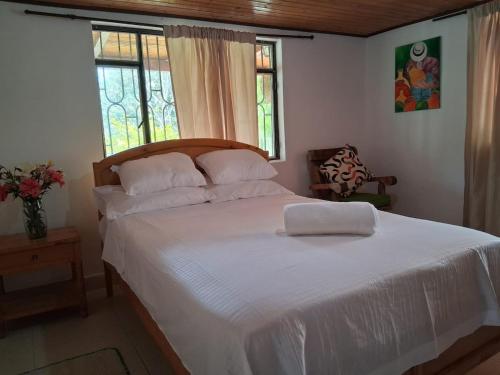 a bedroom with a large bed with white sheets and windows at Fonte di vita in Duitama