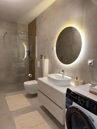 a bathroom with a sink and a toilet and a mirror at Emma Luksuzni apartman Tuzla Musique in Tuzla