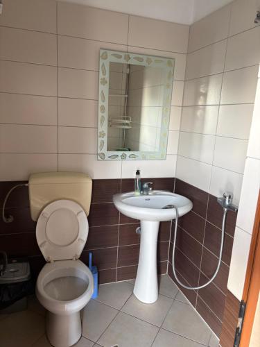 a bathroom with a toilet and a sink and a mirror at Hotel Bar Restaurant Riviera in Shëngjin