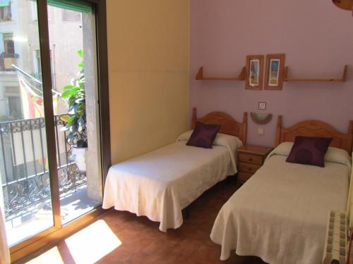 two beds in a room with a balcony at Pension Alamar in Barcelona