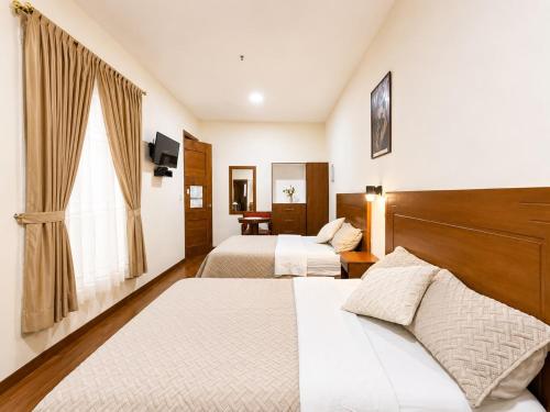 a hotel room with two beds and a window at Suite Tarqui en el Centro Histórico in Cuenca