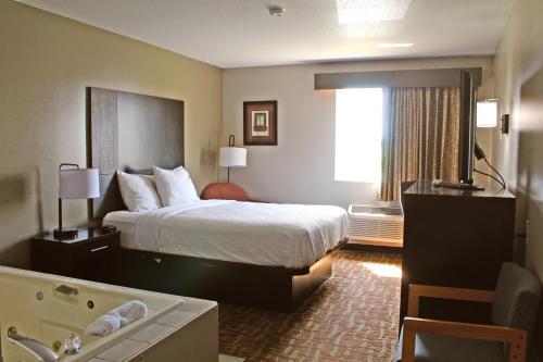 a hotel room with a large bed and a bathroom at Days Inn by Wyndham West-Eau Claire in Eau Claire