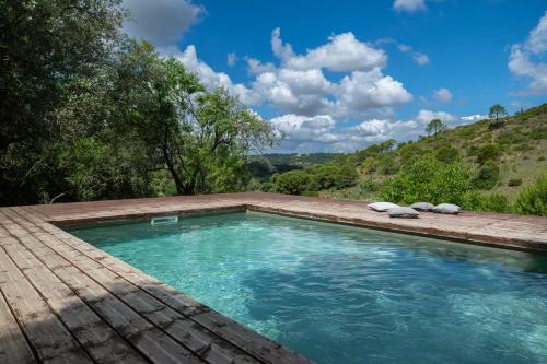 a swimming pool with a wooden deck and blue water at Biovilla Sustentabilidade in Palmela