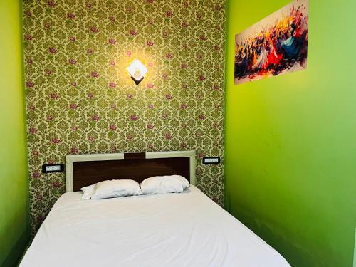 a bedroom with green walls and a bed with two pillows at Aman Convention in Chāndbāli