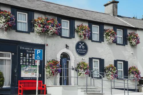 a building with flowers on the windows and a red bench at Madelines Accommodation in Tinahely