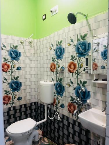 a bathroom with a toilet and flowers on the wall at Aman Convention in Chāndbāli