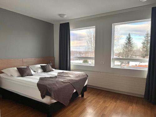 a bedroom with a bed and two large windows at Hótel Valaskjálf in Egilsstaðir