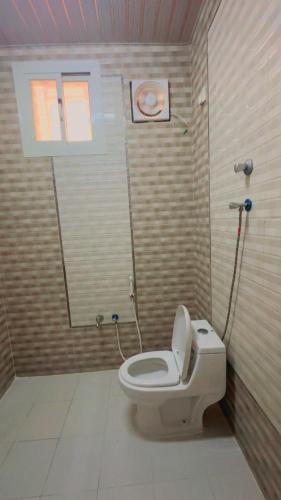 a bathroom with a toilet with a mirror and a window at السلطان هاوس in Najran