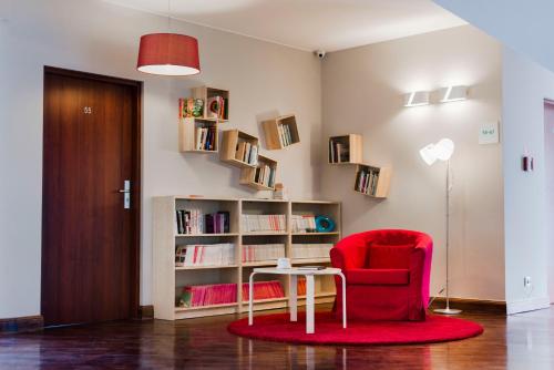 a living room with a red chair and a book shelf at Ach Mazury in Mikołajki