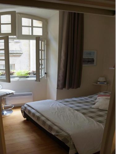 une chambre avec un lit et deux fenêtres dans l'établissement T1bis duplex Hyper centre historique de BX, à Bordeaux