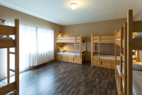 a room with three bunk beds and a window at Falling Lakes Hostel in Korenica