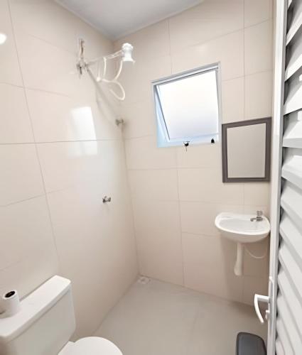 a white bathroom with a toilet and a sink at Suítes confortáveis próximo ao Sesc in Bertioga
