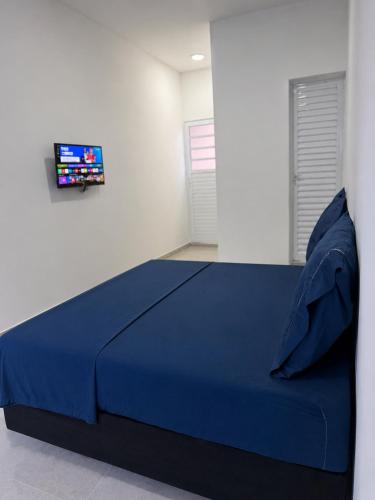 a bedroom with a blue bed with a tv on the wall at Suítes confortáveis próximo ao Sesc in Bertioga
