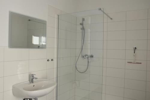 a white bathroom with a shower and a sink at Pension Alte Flugleitung in Stendal