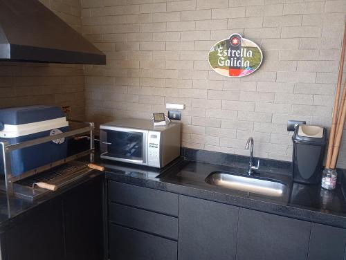 a kitchen counter with a microwave and a sink at Suítes Ninho dos Lobos in Pardinho