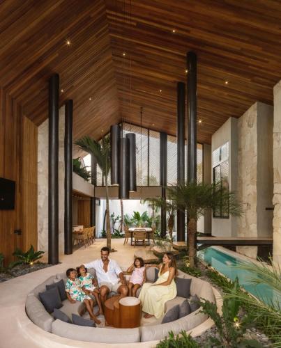 a family sitting on a couch in a living room at Award-Winning 3BR Villa 25m Pool Villa FEH in Kerobokan