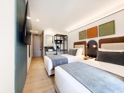a hotel room with two beds and a television at Blues Suites Laureles in Medellín