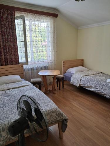 a bedroom with two beds and a table and a window at Green Dilijan B&B in Dilijan