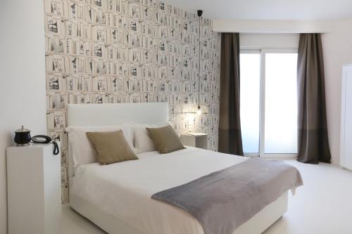 a bedroom with a white bed and a wall of books at Hotel Royal Paestum in Paestum