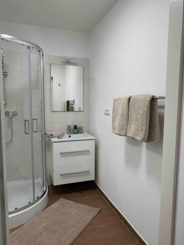 a white bathroom with a shower and a sink at Apartmán Větrná s klimatizací a terasou in Zlín