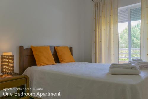 ヴィラモウラにあるAkisol Vilamoura Sun IIIのベッドルーム1室(オレンジ色の枕と窓付)