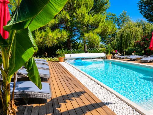 a swimming pool with a wooden deck next to a house at Villa Alyzea Chambre d'hôtes réservée aux adultes in Bessan