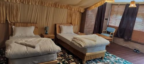 a hotel room with two beds and a chair at Mystique Meadows Swiss Cottages in Nubra