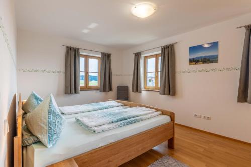 a bedroom with a bed with two windows at Kramerhof - Ferienwohnung Zugspitze in Aufhofen