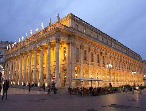 un grand bâtiment avec des personnes debout à l'extérieur dans l'établissement T1bis duplex Hyper centre historique de BX, à Bordeaux